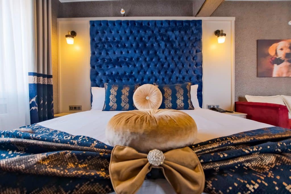 Standart odada mavi kapitone başlıklı çift kişilik yatak ve havlu süslemesi