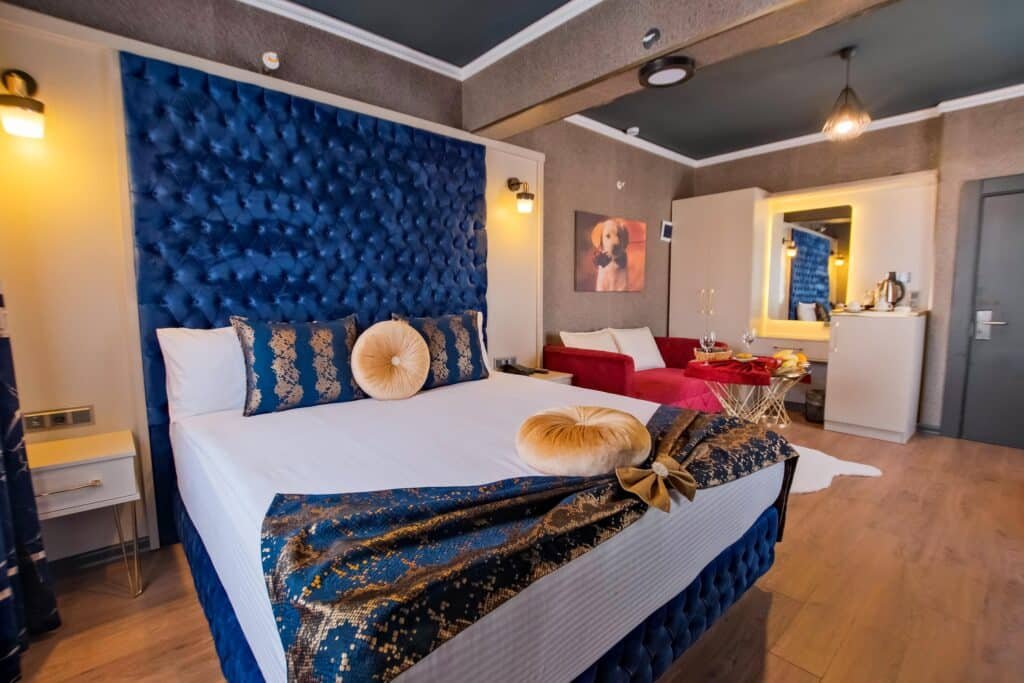 Deluxe odada mavi kapitone başlıklı yatak ve oturma köşesi